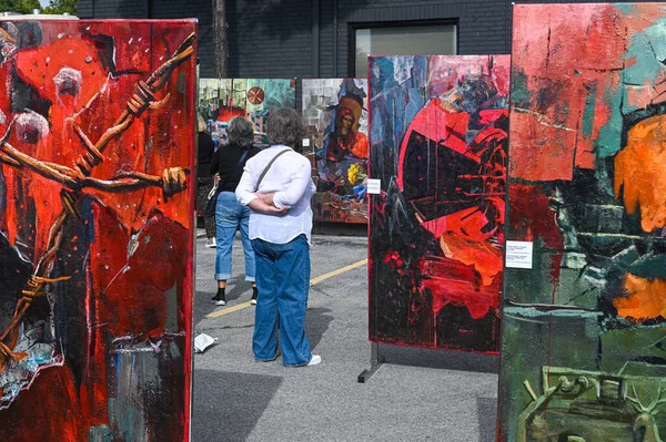 Toronto, ON, Kanada - 13 Eylül 2025: İnsanlar bir açık hava sanat festivalinde modern soyut tabloları sergiliyorlar. Sanat çalışmaları çatışma, mücadele ve yaratıcılık temalarını içerir.