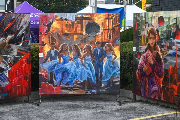 Toronto, ON, Kanada - 13 Eylül 2025: Yanan bir şehirden kaçan gençleri ve bir çocuğu tutan, savaşı, dayanıklılığı ve umudu sembolize eden bir kadını gösteren açık hava sergisi