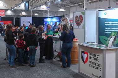 Toronto, ON, Kanada - 14 Kasım 2025: Ontario 'nun tarım gıda yenilikleri ve yerel ürünlerini sergileyen bir tarım fuarı standında sergilenen ziyaretçiler