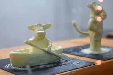 Toronto, ON, Kanada - 14 Kasım 2025: Teknede kürek çeken bir ineğin tarım fuarında yaratıcılık ve süt geleneklerini ön plana çıkardığını gösteren sanatsal tereyağı heykeli