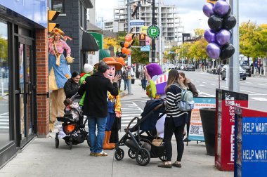 Toronto, ON, Canada - October 25, 2025: Families enjoying a Halloween festival on a city sidewalk, interacting with characters dressed as Woody, Buzz Lightyear, and a scarecrow