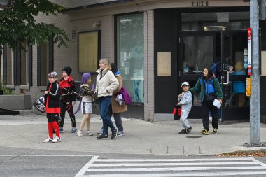 Toronto, ON, Kanada - 25 Ekim 2025: Bir grup çocuk ve yetişkin kaldırımda yürüyor, cadılar bayramı kostümleri giymiş, neşeli atmosferin tadını çıkarıyorlar.