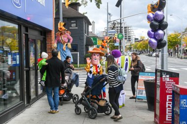 Toronto, ON, Canada - October 25, 2025: People enjoying a community Halloween festival on Bloor Street, families with children seeing characters like Woody and a scarecrow