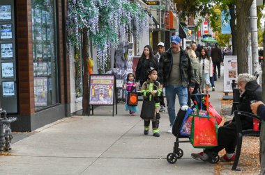 Toronto, ON, Kanada - 25 Ekim 2025: Aileler ve kostümlü çocuklar Toronto 'da neşeli bir sonbahar öğleden sonrasında Bloor Caddesi kaldırımında şaka mı şeker mi?