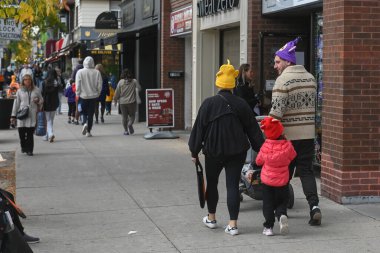 Toronto, ON, Kanada - 25 Ekim 2025: Cadılar Bayramı kostümlü aile kalabalık Bloor Street, Toronto 'da birlikte yürüyor, sonbahar festivali atmosferinin ve şehir kalabalığının tadını çıkarıyor