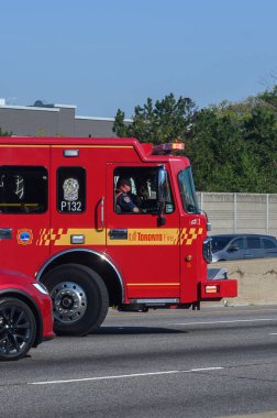 Toronto, ON, Kanada - 3 Haziran 2025: Kırmızı Toronto İtfaiye Aracı sürüş koltuğunda bir itfaiyeciyle birlikte çok şeritli bir otoyolda ilerliyor.