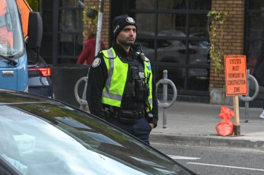 Toronto, ON, Kanada - 27 Eylül 2025: Emniyet yeleği giymiş bir polis memuru trafiğin yakınındaki bir caddede duruyor.