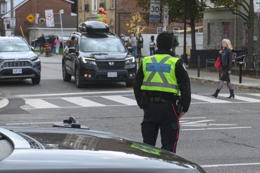 Toronto, ON, Kanada - 27 Eylül 2025: Emniyet yeleği giymiş bir polis memuru trafiğin yakınındaki bir caddede duruyor.