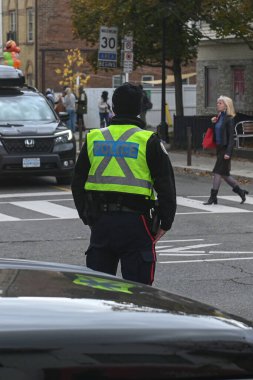 Toronto, ON, Kanada - 27 Eylül 2025: Emniyet yeleği giymiş bir polis memuru trafiğin yakınındaki bir caddede duruyor.