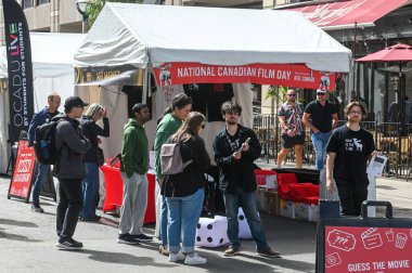 Toronto, ON, Kanada - 7 Eylül 2025: Açık hava etkinliklerinde film temalı etkinliklere katılan insanlar, Kanada Ulusal Film Günü pankartı bulunan bir çadıra sahipler