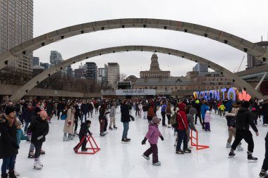 Toronto, ON, Kanada - 3 Aralık 2025: Birçok insan arka planda Toronto tabelası ve şehir mimarisi ile Nathan Phillips Meydanı 'nda buz pateni yapmaktan keyif alıyor