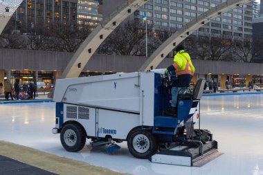 Toronto, ON, Kanada - 3 Aralık 2025: İşçi buz yüzeyi makinası, belediye binası kemerleri altında halka açık buz pateni pisti hazırlamak, pürüzsüz yüzey garantisi