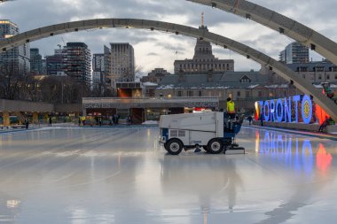 Toronto, ON, Kanada - 3 Aralık 2025: Arkasında Toronto tabelası ve şehir binaları olan Nathan Phillips Meydanı 'nda halka açık bir buz pateni pisti hazırlamak