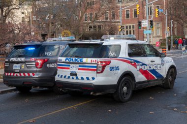 Toronto, ON, Kanada - 15 Ekim 2025: Toronto Polis Teşkilatı devriye araçları ışıkların hazır olduğu bir şehir caddesinde dizilmiş memurlar kamu güvenliği ve düzeni sağlıyorlar