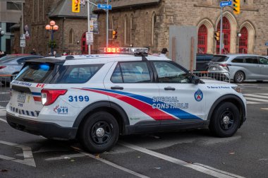 Toronto, ON, Kanada - 15 Ekim 2025: Beyaz polis aracı acil durum ışıkları yanıp sönen, yan tarafında özel polis memuru olan, şehir caddesinde park etmiş