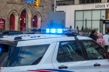 Toronto, ON, Kanada - 15 Ekim 2025: Parlayan mavi ışıklı polis aracı binalar ve insanların yoğun olduğu bir şehir caddesinde acil bir duruma müdahale ediyor