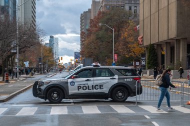 Toronto, ON, Kanada - 15 Ekim 2025: Toronto Polis aracı caddeyi kapatıyor, yaya geçiyor ve arka planda kentsel binalar olan ağaçlar yıkılıyor