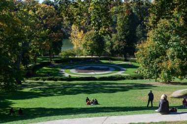 Toronto, ON, Kanada - 10 Ekim 2025: İnsanlar güneşli bir sonbahar gününde piknik yapıp High Park 'ta geziniyorlar. Sonbahar renklerini gösteren ağaçlar