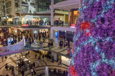 Toronto, ON, Kanada - 24 Aralık 2025: Müşteriler ve ziyaretçiler çok katlı bir alışveriş merkezinin içinde şenlikli dekorasyonların ve devasa bir Noel ağacının tadını çıkarıyorlar.