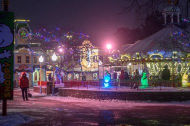 Toronto, ON, Kanada - 31 Aralık 2025: İnsanlar eğlence parkında şenlikli bir kış gecesinin tadını çıkarıyorlar. Parlak ışıklar bir atlıkarınca ve dekore edilmiş binaları aydınlatır