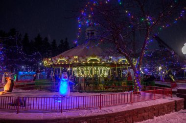 Toronto, ON, Kanada - 31 Aralık 2025 Kış Harikalar Diyarı tema parkı neşeli bir atlıkarınca, parlak ışıklar ve kar ile geceleyin bayram kutlaması