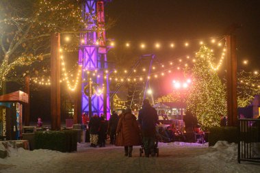 Toronto, ON, Kanada - 31 Aralık 2025: Aydınlatılmış kış festivalinin tadını çıkaran ziyaretçiler festival ışıkları, kar ve geceleri büyük bir Noel ağacı