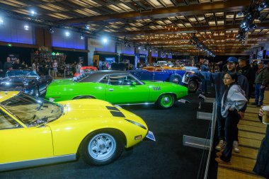 Toronto, ON, Kanada - 13 Şubat 2026: Katılımcılar Toronto 'daki bir otomobil fuarında aralarında yeşil bir kaslı araba ve sarı spor arabanın da bulunduğu antika araçları izliyorlar