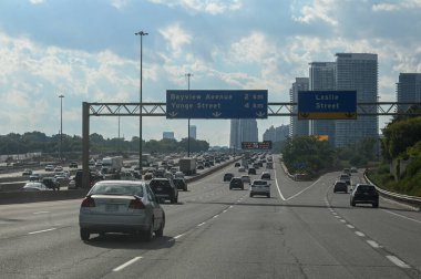 Toronto, ON, Kanada - 10 Ağustos 2025: Pek çok araba yoğun bir otoyolu kısmen güneşli bir günde trafik sıkışıklığıyla doldurdu.