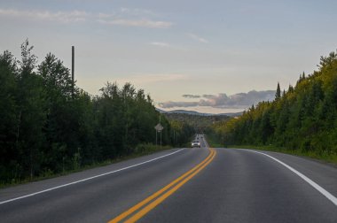 Toronto, ON, Kanada - 10 Ağustos 2025: Asphalt yolu arabayla, yeşil ağaçlarla ve dağlarla olan mesafeye kadar uzanıyor.