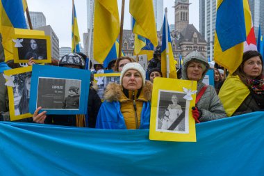 Toronto, ON, Kanada - 22 Şubat 2026: Ukrayna yürüyüş katılımcıları savaş kurbanlarının portrelerini taşıyor ve ulusal bayraklar takıyor, Toronto Eski Belediye Binası önündeki çatışmayı protesto ediyorlar