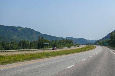 Toronto, ON, Kanada - 10 Ağustos 2025: Dağlık, ormanlık arazide bir otoyol rüzgarı, ulaşımı ve doğayı gözler önüne seriyor.