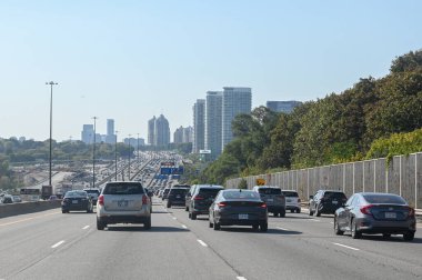 Toronto, ON, Kanada - 10 Ağustos 2025: Yoğun bir otoyolda güneşli bir günde şehrin ufuk çizgisi görülebilen arabalar.