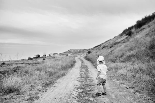bir şapkalı çocuk yolda duran ve uzağa arıyorsunuz 