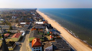 Sarbinowo kıyı şeridinin insansız hava aracı panoraması, Baltık Denizi ve açık mavi gökyüzü altında kumlu sahil.
