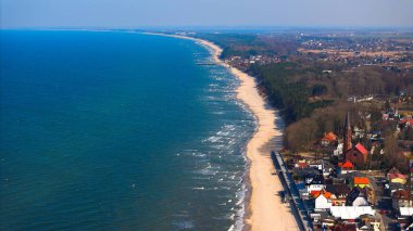 Sarbinowo 'nun sahil ve kıyı şeridini, yumuşak dalgalar ve sakin ufuklarla gösteren insansız hava aracı görüntüsü..
