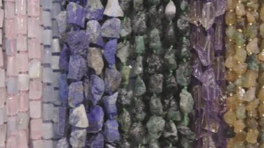 Çeşitli değerli taşlar dizelerde asılı duruyor, ham güzelliklerini ve mücevher yaratmaya hazır olduklarını vurguluyorlar..