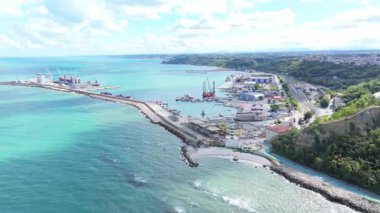 İnsansız hava aracı görüntüleri Ortonas limanını sakin Adriyatik suları, yumuşak kıyı şeridi dalgaları, botlar, gemiler ve açık mavi gökyüzünün altında birkaç beyaz bulutun üzerinde sürüklendiği tam liman altyapısıyla yakalıyor..