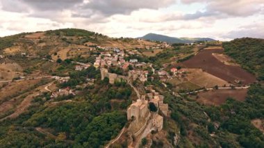 Roccascalegna 'nın altın saat görüntüsü kayalık kaleyi, eski kasabayı ve çevresindeki tarım arazilerini vurguluyor..