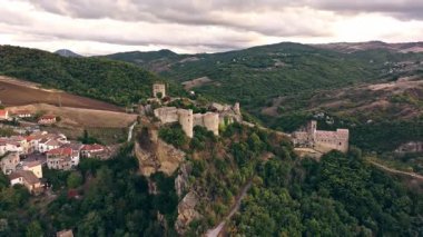 Roccascalegna Kalesi 'nin insansız hava aracı manzarası tarihi bir köy, yeşil tepeler, otlaklar ve ekili tarlalara bakıyor..