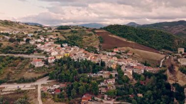 Günbatımında Roccascalegna kalesini, köy sokaklarını ve geniş dağ manzarasını gösteren hava manzarası..