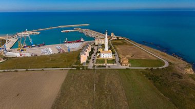 Vasto Limanı 'nın havadan çekilmiş fotoğrafı deniz lojistiği, turkuaz kıyı şeridi, liman tesisleri ve açık kırsal araziyi gösteriyor..