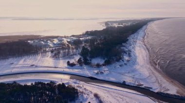Donmuş Jamno Gölü 'nün kış manzarası karlı kum tepeleri ve sakin Baltık sularıyla parlak güneş ışığında buluşuyor..