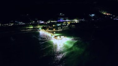 Romantik Adriyatik gecesinde aydınlatılmış bir trabocco ve aşağıdaki yumuşak su.