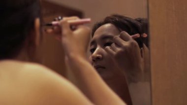 Günlük güzellik ritüeli, bir kadın titizlikle aynanın önüne göz kalemi sürer, odaklanmış gözleriyle gözlerini güçlendirir.