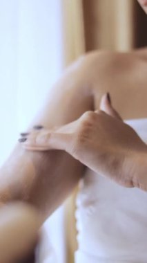 Koluna nemlendirici krem süren bir kadın. Sağlıklı görünüş ve güzel cilt için cilt bakımı rutini.