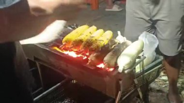 Bir sokak satıcısı tarafından geceleyin sıcak kömür üzerinde kızartılan taze mısırın cızırtısını ve kokusunu hissedin.