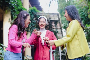 Sevinç saçan üç genç kadın ortak bir maceraya hazırlanıyor. Kahkahaları ve renkli kıyafetleri ileride unutulmaz yolculuk anılarını ima eden canlı bir sahne yaratıyor..