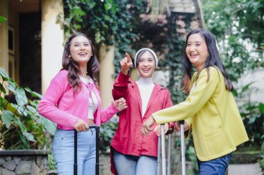 Üç güzel genç bayan bavullarıyla birlikte sevinçten havalara uçuyor ve tatillerine hazırlar. Bir arkadaş heyecanla işaret ediyor. Keşif beklentilerini simgeliyor..