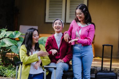 Renkli gündelik giysiler giymiş üç genç kadın bavullarıyla bir yolculuğa çıkmak için heyecanlı bir şekilde toplanıyorlar. Hikayelerini paylaşıyorlar ve birlikte seyahat planları yapıyorlar..