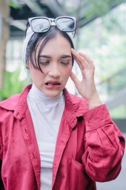 Şiddetli baş ağrısı çeken bir kadın, stres ve acı taşıyan bir yüz ifadesi. Çağdaş hayatın kronik migreni ile ilgili günlük mücadeleleri ve zorlukları temsil ediyor..